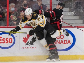 Boston Bruins defenceman Brandon Carlo is taken into the boards by the Ottawa Senators' Parker Kelly in a February 2022 game. The Senators will play their home opener against Boston on Oct. 18.