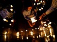 Community members light candles at a memorial site near the parade route the day after a mass shooting at a Fourth of July parade in the Chicago suburb of Highland Park, Ill., Tuesday, July 5, 2022.