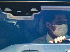 Haruyuki Takahashi, a former Tokyo Olympic organizing committee board member, rides on the back seats of a car as he leaves his home in Tokyo Wednesday, Aug. 17, 2022. Takahashi and three people from a clothing company that was a surprise sponsor of the 2020 Games were arrested on bribery suspicions Wednesday.