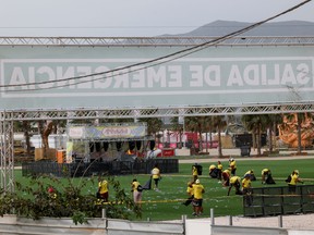 Staff members clean the venue of Medusa Festival, an electronic music festival, after high winds caused part of a stage to collapse, in Cullera, near Valencia, Spain, Saturday, Aug. 13, 2022.