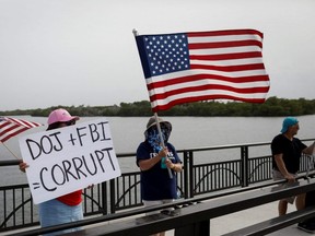 Supporters of former U.S. President Donald Trump wave flags as they gather outside his Mar-a-Lago home after Trump said that FBI agents raided it in Palm Beach, Fla., Monday, Aug. 9, 2022.