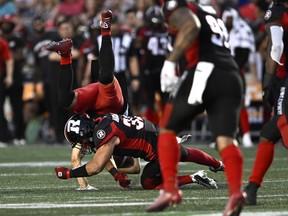 Calgary Stampeders wide receiver Colton Hunchak (89) gets knocked down after a tackle by Ottawa Redblacks linebacker Adam Auclair (32) during first half CFL football action in Ottawa on Friday August 5, 2022.
