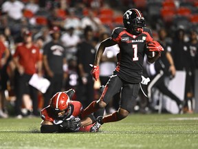Ottawa Redblacks wide receiver Darvin Adams (1) tries to evade the tackle of Calgary Stampeders linebacker Jameer Thurman (56) during second half CFL football action in Ottawa on Friday, Aug. 5, 2022.