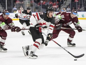 Canada's Ridly Grieg (17) is chased by Latvia's Peteris Purmalis (20) and Bogdans Hodass (17) during second period IIHF World Junior Hockey Championship action in Edmonton on Wednesday, Aug. 10, 2022.