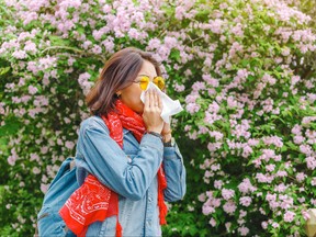 Young woman sneezes and blows her nose with a handkerchief.