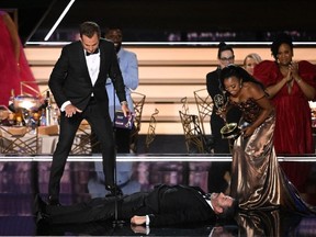 Quinta Brunson (R), flanked by actor Will Arnett (L), looks at Jimmy Kimmel lying onstage after she accepted the award for Outstanding Writing For A Comedy Series for "Abbott Elementary" during the 74th Emmy Awards at the Microsoft Theater in Los Angeles on September 12, 2022.