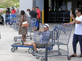Shoppers take photos while waiting in line outside a retail warehouse as people rush to prepare for Tropical Storm Ian, in Kissimmee, Fla., Sunday Sept. 25, 2022.