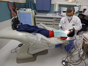 A dentist at the Riley Hospital for Children Department of Pediatric Dentistry, checks the teeth of Justin Perez, 11, during an office visit in Indianapolis, Friday, Jan. 22, 2016. University of Calgary associate economics professor Lindsay Tedds warns the federal dental benefit for children opens families up to the potential for "clawbacks" if they don't spend all the money on their kids' teeth.