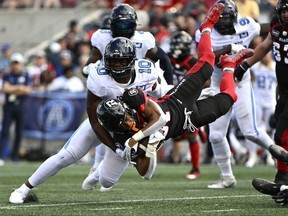 Redblacks running back Devonte Williams gets knocked off his feet as he runs with the ball in front of Argonauts’ Henoc Muamba on Sept. 10.