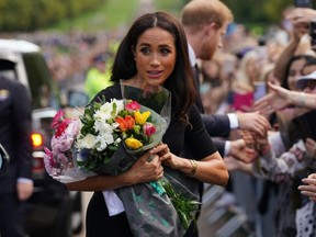Meghan, Duchess of Sussex collects flowers as she chats with well-wishers on the Long walk at Windsor Castle on September 10, 2022, two days after the death of Britain's Queen Elizabeth II at the age of 96. (Photo by KIRSTY O'CONNOR/POOL/AFP via Getty Images)