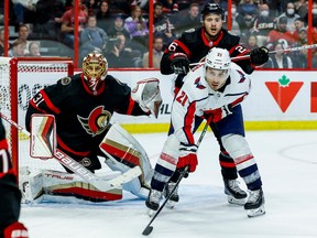 Senators netminder Anton Forsberg, left, tracks the puck as teammate Erik Brannstrom checks Capitals right-winger Garnet Hathaway in front of the goal during the second period of Thursday's game at Canadian Tire Centre.