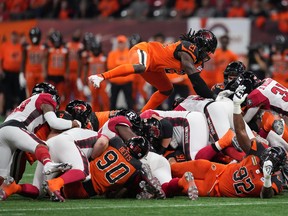 Lions defender Jordan Williams leaps on top of the pile as Redblacks quarterback Caleb Evans, centre right, pushes ahead for a first down during the first half on on Friday night.