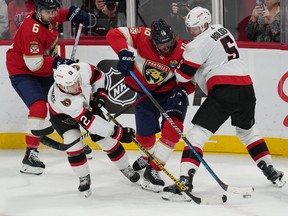 Ottawa Senators right wing Alex DeBrincat (12) and defenceman Nick Holden (5) battle for possession against Florida Panthers defenceman Marc Staal (18) as centre Colin White (6) looks on during the second period at FLA Live Arena.