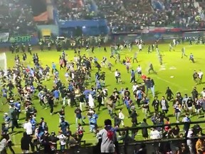 In this screen grab taken from social media, fans run onto a soccer field in Indonesia on Saturday, Oct. 1, 2022.
