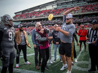 Ian Telfer, who uOttawa's Telfer School of Management is named after, conducted the pre-game coin toss with assistance from Ottawa Redblacks lineman Zack Pelehos, right, a former Gee-Gee. A $750,000 gold coin weighing about 20 pounds was used for the flip.