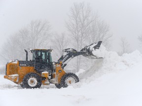 A loader digs out a parking lot after an intense lake-effect snowstorm impacted the area of Hamburg, N.Y., on Friday. Hamburg is normally about a two-hour drive from Erie, Pa., where the Otters had two Ontario Hockey League games postponed because of the storm.
