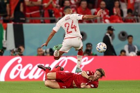 Tunisia defender Ali Abdi jumps over Denmark defender Joachim Andersen during the 2022 World Cup.