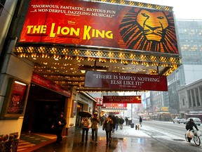 Pedestrians walk beneath a sign for the musical 'The Lion King' March 6, 2003 in New York City.