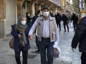 People walk in front of closed shops of the Grand Bazaar in Tehran, Iran, as anti-riot police patrol the protest scene, November 15, 2022.