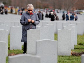 A woman quietly holds rosary beads in front of one of the headstones in the military cemetery after the service. 
The National Military Cemetery's Annual Remembrance Day Service was packed with military members and the general public Friday as people came to pay their respects to the fallen and our military.