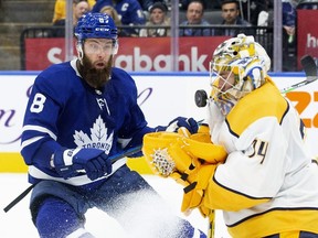 Nashville Predators goaltender Juuse Saros stops a shot as Toronto Maple Leafs defenceman Jake Muzzin (8) skates in during second period NHL hockey action in Toronto, Tuesday, Nov. 16, 2021. The Leafs will be without Muzzin for at least the next three months.