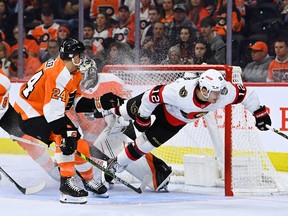 Pemain sayap Senator Alex DeBrincat (12) terbang melewati lipatan di depan pemain bertahan Flyers Nick Seeler dan kiper Carter Hart pada periode ketiga pertandingan hari Sabtu.