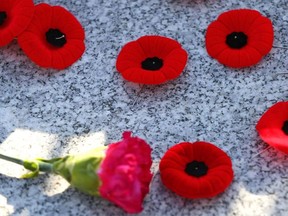 Poppies and a carnation lay on a memorial during Remembrance Day ceremonies at the Field of Crosses in Calgary, Nov. 11, 2021.