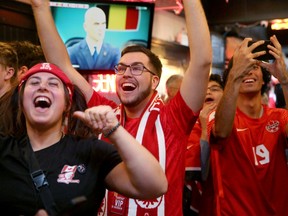 Dari kiri, Jessie Porter, Josh Geauvreau, dan Vahid Seddigh menyemangati Kanada saat mereka menonton pertandingan di Glebe Central Pub pada Rabu sore.