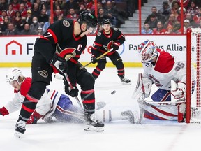 Brady Tkachuk of the Ottawa Senators shoots the puck between his legs as Kaiden Guhle of the Montreal Canadiens blocks the puck and goalie Sam Montembeault looks on during the second period at Canadian Tire Centre on Wednesday night.