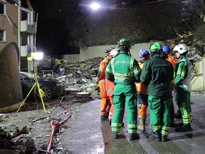 This video grab taken from a footage released on Dec. 12, 2022 by the Government of Jersey shows fire crews standing in front of the rubble of a low-rise apartment building after an explosion, in the Channel island's port capital Saint Helier.