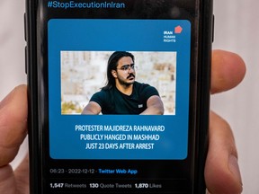 A person in the Cypriot capital Nicosia checks a mobile phone on December 12, 2022, displaying a Tweet about the execution announced by Iranian authorities of Majidreza Rahnavard, the second capital punishment linked to nearly three months of protests.