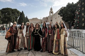 Women dressed in traditional clothing pose for a picture by the Christmas tree at the Manger Square outside the Church of the Nativity in the biblical city of Bethlehem in the occupied West Bank on Dec. 24, 2022.