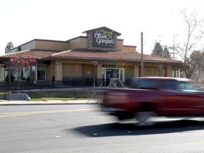 A car drives by an Olive Garden restaurant.