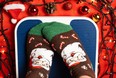 A woman in Christmas socks stands on the scales, weighs herself after gluttony during the holidays