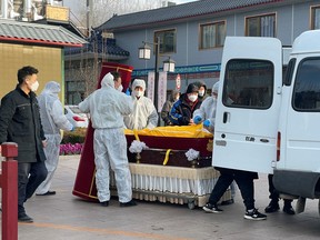 Workers in protective suits transfer a body in a casket at a funeral home, amid the COVID-19 outbreak in Beijing, Dec. 17, 2022.