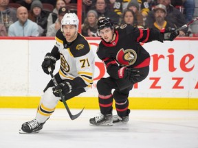 L'ailier droit des Sénateurs d'Ottawa Drake Batherson et l'ailier gauche des Bruins de Boston Taylor Hall (71) et (19) suivent la rondelle en première période au Centre Canadian Tire.