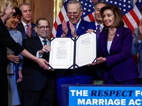 U.S. House Speaker Nancy Pelosi (D-CA) and fellow members of Congress hold "The Respect for Marriage Act" during a bill enrolment ceremony on Capitol Hill, in Washington, D.C., Thursday, Dec. 8, 2022.