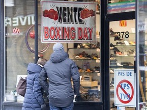 People look through the window of a store on Boxing Day in Montreal on Dec. 26, 2021.