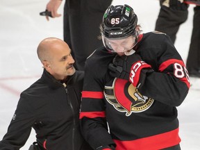 Ottawa Senators defenceman Jake Sanderson is escorted off the ice after being hit by the puck in the third period against the Washington Capitals at the Canadian Tire Centre on Dec. 22, 2022. Sanderson was bruised heading into Tuesday's game against Boston, but said he was 'feeling 100 per cent'.