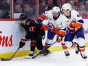 The Ottawa Senators' Ridly Greig (17) keeps the puck away from New York Islanders defenseman Alexander Romanov (28) and center Jean-Gabriel Pageau (44) during the first period at the Canadian Tire Center on Wednesday, Jan.  25, 2023. 