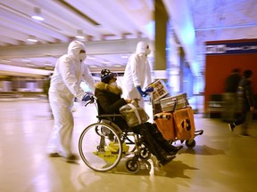Workers wearing protective masks and suits help a Chinese traveller leaving the arrival hall of Rome Fiumicino International Airport, near Rome, on December 29, 2022 after being tested for the COVID-19 coronavirus.