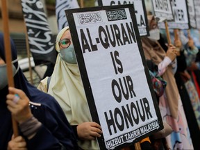 A woman holds a placard that reads " Al-Quran is our honour" during a protest in front of the Swedish embassy after Rasmus Paludan, leader of Danish far-right political party Hard Line burned a copy of the Qur'an near the Turkish Embassy in Stockholm, in Kuala Lumpur, Malaysia, Jan. 27, 2023.