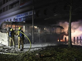 Firefighters extinguish a bus that had been set on fire by unknown persons in Berlin Sunday, Jan. 1, 2023.