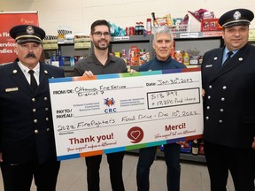 Sector Fire Chief Larry Roy (left) and Lt. Denis Charbonneau (right) from Ottawa Fire Services present a cheque to Chad Chartrand (second to the left), community & fund development co-ordinator, and Luc Ouellette, executive director, of the Orleans-Cumberland Community Resource Centre in Orleans on Monday.
