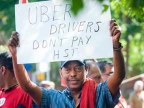 File photo/ Adamu Berhanu holds a sign reading Uber drivers don't pay HST at the protest outside City Hall Wednesday August 16, 2015.