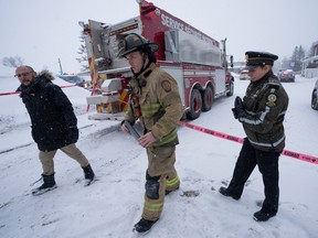 Firefighter Francois Thiverge and Mayor Sebastien Marcil, left, leave the secure zone after an explosion at a propane company Thursday, Jan. 12, 2023  in Saint-Roch-de-L'Achigan, Que.