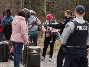Asylum seekers talk to a police officer as they cross into Canada from the U.S. border, near a checkpoint on Roxham Road on April 24, 2022.