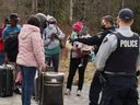 Pencari suaka berbicara dengan petugas polisi saat mereka menyeberang ke Kanada dari perbatasan AS, dekat pos pemeriksaan di Roxham Road pada 24 April 2022.
