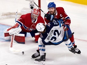Montreal Canadiens goaltender Carey Price reaches out to reel in the puck as defenceman Shea Weber levels Winnipeg Jets centre Mason Appleton during Game 3 of second-round playoff series in Montreal on June 6, 2021.