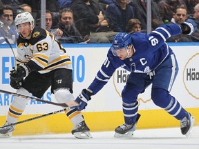 Brad Marchand #63 of the Boston Bruins flips a puck high and away from a checking John Tavares #91 of the Toronto Maple Leafs during an NHL game at Scotiabank Arena on February 1, 2023 in Toronto.